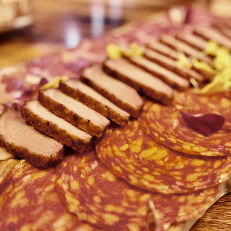 Close-up of a charcuterie board with sliced meats, including salami and duck breast.